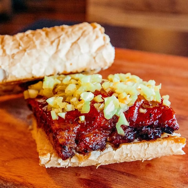 Gettin' Basted's BBQ sandwich with glistening meat, sauce, and diced green relish on a toasted bun.